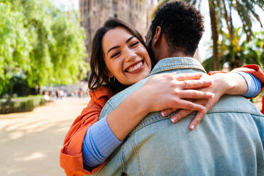 Multiracial beautiful happy couple of lovers dating at Sagrada Familia, Barcelona - Multiethnic tourists travelling in Europe and visiting a city in Spain, concepts about tourism and people lifestyle - DMDF08166