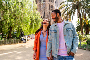 Multiracial beautiful happy couple of lovers dating at Sagrada Familia, Barcelona - Multiethnic tourists travelling in Europe and visiting a city in Spain, concepts about tourism and people lifestyle - DMDF08171