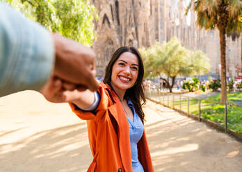 Multiracial beautiful happy couple of lovers dating at Sagrada Familia, Barcelona - Multiethnic tourists travelling in Europe and visiting a city in Spain, concepts about tourism and people lifestyle - DMDF08174