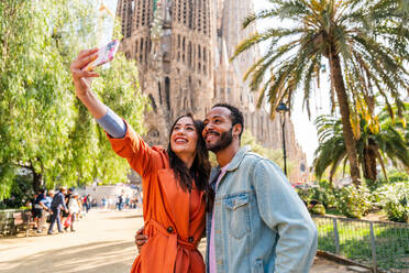 Multirassisches glückliches Liebespaar an der Sagrada Familia, Barcelona - Multiethnische Touristen, die in Europa reisen und eine Stadt in Spanien besuchen, Konzepte über Tourismus und Lebensstil der Menschen - DMDF08177