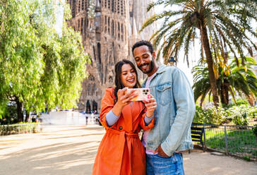 Multirassisches glückliches Liebespaar an der Sagrada Familia, Barcelona - Multiethnische Touristen, die in Europa reisen und eine Stadt in Spanien besuchen, Konzepte über Tourismus und Lebensstil der Menschen - DMDF08181