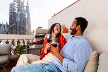 Multiracial beautiful happy couple of lovers dating on rooftop balcony at Sagrada Familia, Barcelona - Multiethnic people having romantic aperitif on a terrace with city view , concepts about tourism and people lifestyle - DMDF08202