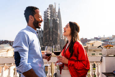 Multirassisches glückliches Liebespaar auf einem Dachbalkon an der Sagrada Familia, Barcelona - Multiethnische Menschen bei einem romantischen Aperitif auf einer Terrasse mit Blick auf die Stadt, Konzepte über Tourismus und Lebensstil der Menschen - DMDF08209