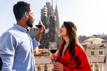 Multirassisches glückliches Liebespaar auf einem Dachbalkon an der Sagrada Familia, Barcelona - Multiethnische Menschen bei einem romantischen Aperitif auf einer Terrasse mit Blick auf die Stadt, Konzepte über Tourismus und Lebensstil der Menschen - DMDF08211