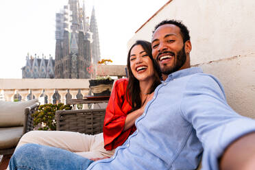 Multirassisches glückliches Liebespaar auf einem Dachbalkon an der Sagrada Familia, Barcelona - Multiethnische Menschen bei einem romantischen Treffen auf einer Terrasse mit Blick auf die Stadt, Konzepte für Tourismus und Lebensstil der Menschen - DMDF08219