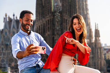 Multirassisches glückliches Liebespaar auf einem Dachbalkon an der Sagrada Familia, Barcelona - Multiethnische Menschen bei einem romantischen Treffen auf einer Terrasse mit Blick auf die Stadt, Konzepte für Tourismus und Lebensstil der Menschen - DMDF08278