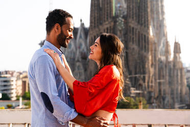 Multiracial beautiful happy couple of lovers dating on rooftop balcony at Sagrada Familia, Barcelona - Multiethnic people having romantic aperitif dinner on a terrace with city view , concepts about tourism and people lifestyle - DMDF08293