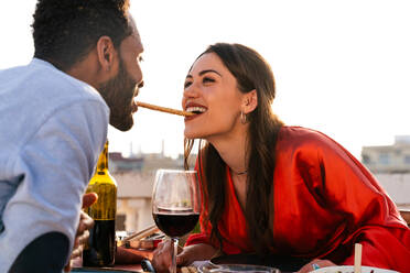 Multirassisches glückliches Liebespaar auf einem Dachbalkon an der Sagrada Familia, Barcelona - Multiethnische Menschen beim romantischen Aperitif-Dinner auf einer Terrasse mit Blick auf die Stadt, Konzepte über Tourismus und Lebensstil der Menschen - DMDF08322