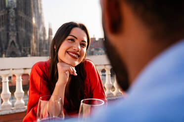 Multirassisches glückliches Liebespaar auf einem Dachbalkon an der Sagrada Familia, Barcelona - Multiethnische Menschen beim romantischen Aperitif-Dinner auf einer Terrasse mit Blick auf die Stadt, Konzepte über Tourismus und Lebensstil der Menschen - DMDF08338