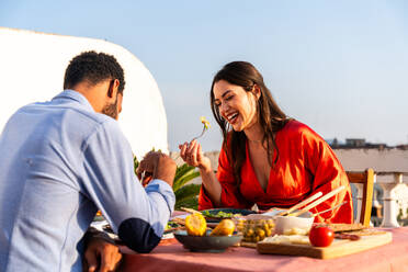 Multirassisches glückliches Liebespaar auf einem Dachbalkon an der Sagrada Familia, Barcelona - Multiethnische Menschen beim romantischen Aperitif-Dinner auf einer Terrasse mit Blick auf die Stadt, Konzepte über Tourismus und Lebensstil der Menschen - DMDF08348