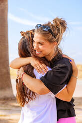 Two women in fitness wear hugging each other standing on rooftop