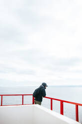 Ein Mann steht auf dem Deck einer Fähre und blickt nachdenklich über das ruhige Wasser von Vancouver Island, British Columbia, und genießt die Gelassenheit der Reise. - ADSF50839