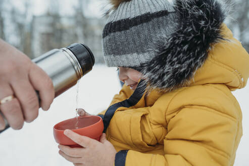 Vater gießt Tee in die Tasse seines Sohnes - ANAF02614