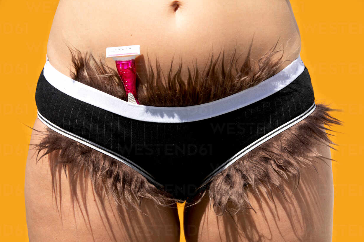 Crop anonymous woman with razor and pubic hair sticking out from