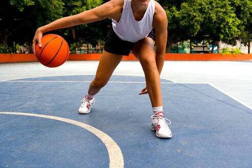 Crop unerkennbar sportliche Frau in activewear dribbeln beim Basketball spielen auf dem Platz während der sonnigen Sommertag - ADSF50929
