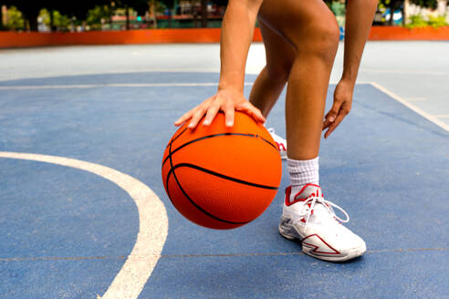 Crop unerkennbar sportliche Frau in activewear dribbeln beim Basketball spielen auf dem Platz während der sonnigen Sommertag - ADSF50930