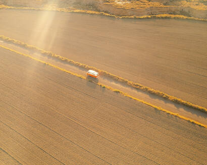 Luftaufnahme eines orangefarbenen Oldtimer-Wohnmobils in der Wüste Bardenas Reales bei Sonnenaufgang, Navarra, Spanien. - AAEF24828