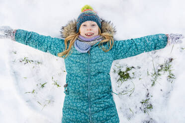 Playful girl wearing parka jacket and making snow angel - IHF01849