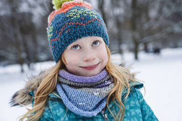 Smiling blond girl wearing scarf and knit hat in winter - IHF01850