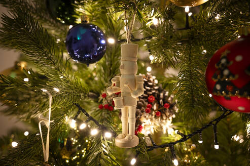 Wooden toy soldier hanging on Christmas tree at home - ALKF00908