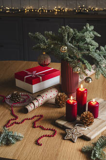 Red candles with gift box near decorated potted Christmas tree on table - ALKF00912