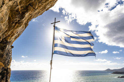 Griechenland, Kreta, die griechische Flagge flattert vor der Sonne über dem Mittelmeer - EGBF00999