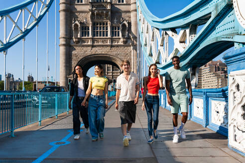 Multirassische Gruppe von glücklichen jungen Freunden in der Londoner City - Multiethnische Teenager treffen sich und haben Spaß in der Tower Bridge, UK - Konzepte über jugendlichen Lebensstil, Reisen und Tourismus - DMDF08359