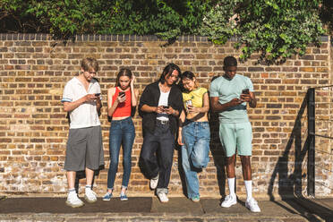 Multirassische Gruppe von glücklichen jungen Freunden in der Londoner City - Multiethnische Teenager treffen sich und haben Spaß in der Tower Bridge, UK - Konzepte über jugendlichen Lebensstil, Reisen und Tourismus - DMDF08377