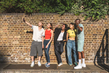 Multiracial group of happy young friends bonding in London city - Multiethnic teens students meeting and having fun in Tower Bridge area, UK - Concepts about youth lifestyle, travel and tourism - DMDF08378