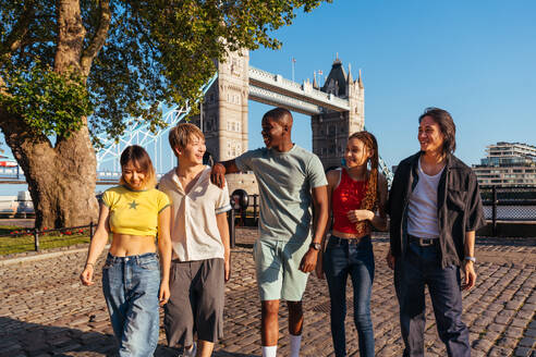 Multirassische Gruppe von glücklichen jungen Freunden in der Londoner City - Multiethnische Teenager treffen sich und haben Spaß in der Tower Bridge, UK - Konzepte über jugendlichen Lebensstil, Reisen und Tourismus - DMDF08382