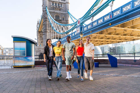 Multirassische Gruppe von glücklichen jungen Freunden in der Londoner City - Multiethnische Teenager treffen sich und haben Spaß in der Tower Bridge, UK - Konzepte über jugendlichen Lebensstil, Reisen und Tourismus - DMDF08389