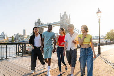 Multirassische Gruppe von glücklichen jungen Freunden in der Londoner City - Multiethnische Teenager treffen sich und haben Spaß in der Tower Bridge, UK - Konzepte über jugendlichen Lebensstil, Reisen und Tourismus - DMDF08394