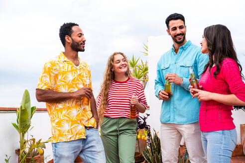 Multiethnische Gruppe von glücklichen jungen Freunden mit Abendessen Grillparty auf dem Dach zu Hause - Multirassische fröhliche junge erwachsene Menschen, die Spaß haben und sich auf einer Terrasse Balkon mit Blick auf die Stadt, Essen und Trinken. - DMDF08529