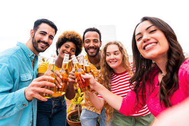 Multiethnische Gruppe von glücklichen jungen Freunden mit Abendessen Grillparty auf dem Dach zu Hause - Multirassische fröhliche junge erwachsene Menschen, die Spaß haben und sich auf einer Terrasse Balkon mit Blick auf die Stadt, Essen und Trinken. - DMDF08547