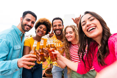 Multiethnische Gruppe von glücklichen jungen Freunden mit Abendessen Grillparty auf dem Dach zu Hause - Multirassische fröhliche junge erwachsene Menschen, die Spaß haben und sich auf einer Terrasse Balkon mit Blick auf die Stadt, Essen und Trinken. - DMDF08549