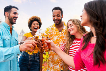 Multiethnische Gruppe von glücklichen jungen Freunden mit Abendessen Grillparty auf dem Dach zu Hause - Multirassische fröhliche junge erwachsene Menschen, die Spaß haben und sich auf einer Terrasse Balkon mit Blick auf die Stadt, Essen und Trinken. - DMDF08552