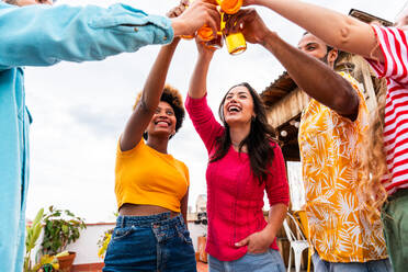 Multiethnische Gruppe von glücklichen jungen Freunden mit Abendessen Grillparty auf dem Dach zu Hause - Multirassische fröhliche junge erwachsene Menschen, die Spaß haben und sich auf einer Terrasse Balkon mit Blick auf die Stadt, Essen und Trinken. - DMDF08566