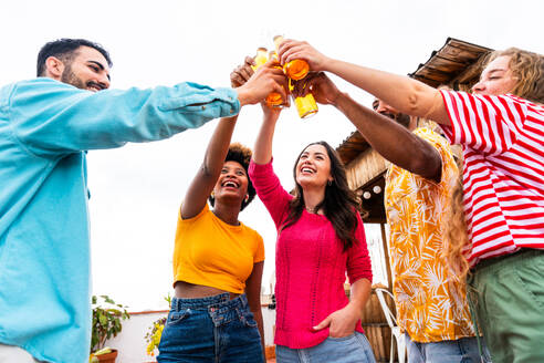 Multiethnische Gruppe von glücklichen jungen Freunden mit Abendessen Grillparty auf dem Dach zu Hause - Multirassische fröhliche junge erwachsene Menschen, die Spaß haben und sich auf einer Terrasse Balkon mit Blick auf die Stadt, Essen und Trinken. - DMDF08567