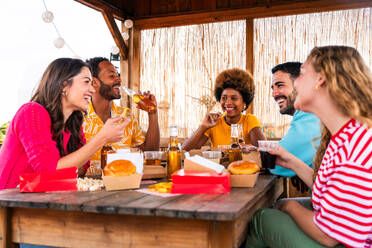 Multiethnische Gruppe von glücklichen jungen Freunden mit Abendessen Grillparty auf dem Dach zu Hause - Multirassische fröhliche junge erwachsene Menschen, die Spaß haben und sich auf einer Terrasse Balkon mit Blick auf die Stadt, Essen und Trinken. - DMDF08570