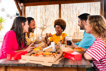 Multiethnische Gruppe von glücklichen jungen Freunden mit Abendessen Grillparty auf dem Dach zu Hause - Multirassische fröhliche junge erwachsene Menschen, die Spaß haben und sich auf einer Terrasse Balkon mit Blick auf die Stadt, Essen und Trinken. - DMDF08574