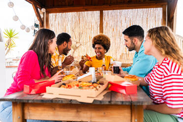 Multiethnische Gruppe von glücklichen jungen Freunden mit Abendessen Grillparty auf dem Dach zu Hause - Multirassische fröhliche junge erwachsene Menschen, die Spaß haben und sich auf einer Terrasse Balkon mit Blick auf die Stadt, Essen und Trinken. - DMDF08575