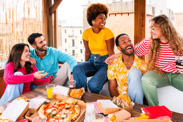 Multiethnische Gruppe von glücklichen jungen Freunden mit Abendessen Grillparty auf dem Dach zu Hause - Multirassische fröhliche junge erwachsene Menschen, die Spaß haben und sich auf einer Terrasse Balkon mit Blick auf die Stadt, Essen und Trinken. - DMDF08614