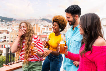 Multiethnische Gruppe von glücklichen jungen Freunden mit Abendessen Grillparty auf dem Dach zu Hause - Multirassische fröhliche junge erwachsene Menschen, die Spaß haben und sich auf einer Terrasse Balkon mit Blick auf die Stadt, Essen und Trinken. - DMDF08633