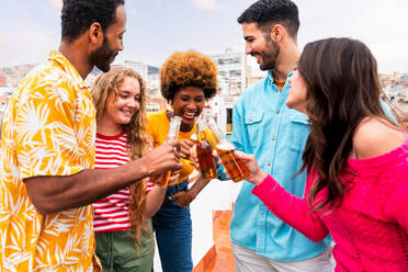 Multiethnische Gruppe von glücklichen jungen Freunden mit Abendessen Grillparty auf dem Dach zu Hause - Multirassische fröhliche junge erwachsene Menschen, die Spaß haben und sich auf einer Terrasse Balkon mit Blick auf die Stadt, Essen und Trinken. - DMDF08636