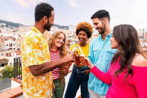 Multiethnische Gruppe von glücklichen jungen Freunden mit Abendessen Grillparty auf dem Dach zu Hause - Multirassische fröhliche junge erwachsene Menschen, die Spaß haben und sich auf einer Terrasse Balkon mit Blick auf die Stadt, Essen und Trinken. - DMDF08637