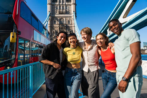 Multirassische Gruppe von glücklichen jungen Freunden in der Londoner City - Multiethnische Teenager treffen sich und haben Spaß in der Tower Bridge, UK - Konzepte über jugendlichen Lebensstil, Reisen und Tourismus - DMDF08668