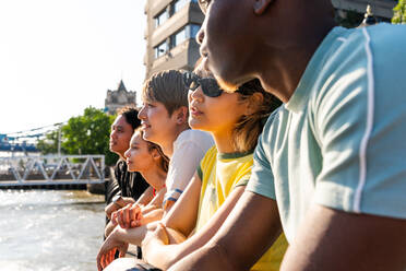 Multirassische Gruppe von glücklichen jungen Freunden in der Londoner City - Multiethnische Teenager treffen sich und haben Spaß in der Tower Bridge, UK - Konzepte über jugendlichen Lebensstil, Reisen und Tourismus - DMDF08678