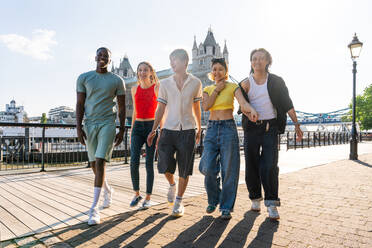 Multiracial group of happy young friends bonding in London city - Multiethnic teens students meeting and having fun in Tower Bridge area, UK - Concepts about youth lifestyle, travel and tourism - DMDF08682