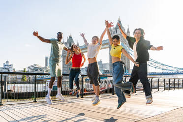 Multirassische Gruppe von glücklichen jungen Freunden in der Londoner City - Multiethnische Teenager treffen sich und haben Spaß in der Tower Bridge, UK - Konzepte über jugendlichen Lebensstil, Reisen und Tourismus - DMDF08685