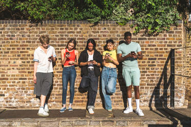 Multirassische Gruppe von glücklichen jungen Freunden in der Londoner City - Multiethnische Teenager treffen sich und haben Spaß in der Tower Bridge, UK - Konzepte über jugendlichen Lebensstil, Reisen und Tourismus - DMDF08686